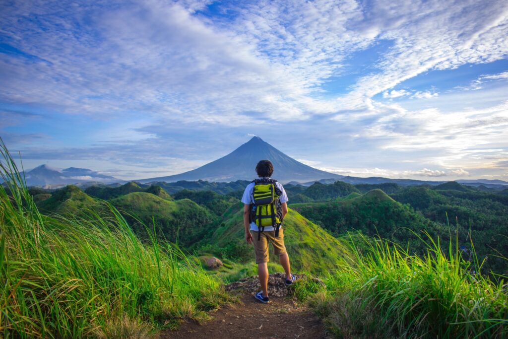 image of a man wearing white shirt and brown pant overlooking a mountain-min